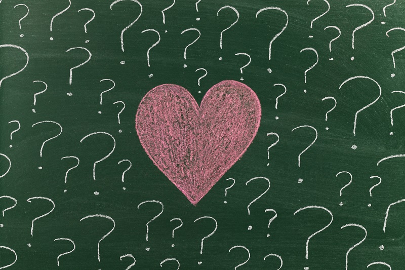 Chalk drawn heart with white question marks around it