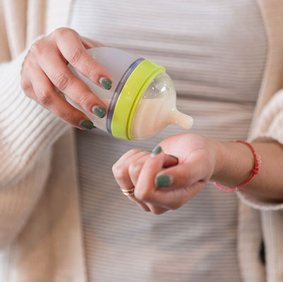 Mother testing the temperature of her baby's breast milk or formula on her wrist