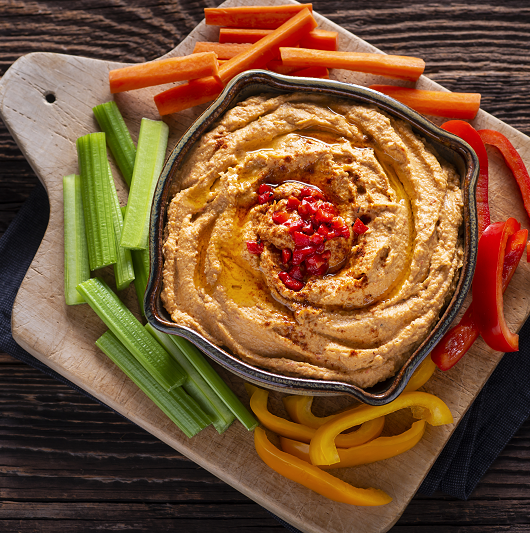 Roasted red pepper hummus with cut peppers around out.