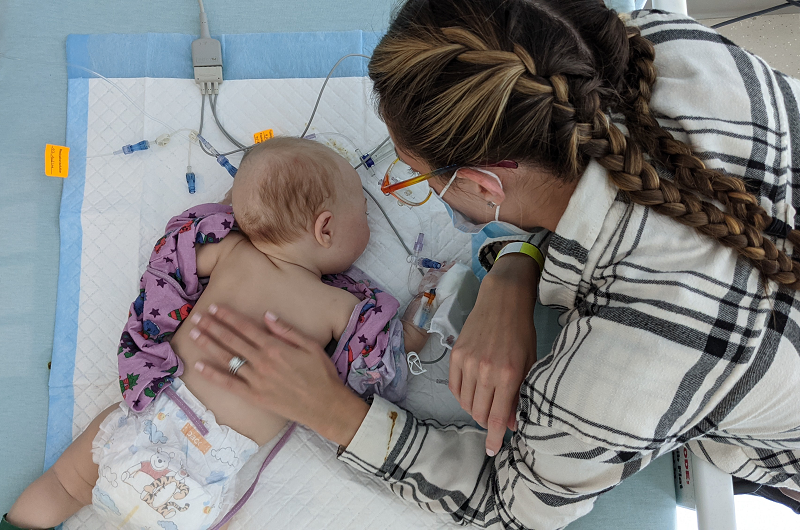 Katie looking over and comforting her hospitalized baby after surgery.