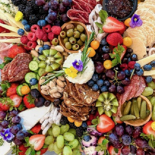 A charcuterie board filled with different cheese, vegetables, fruits and crackers.