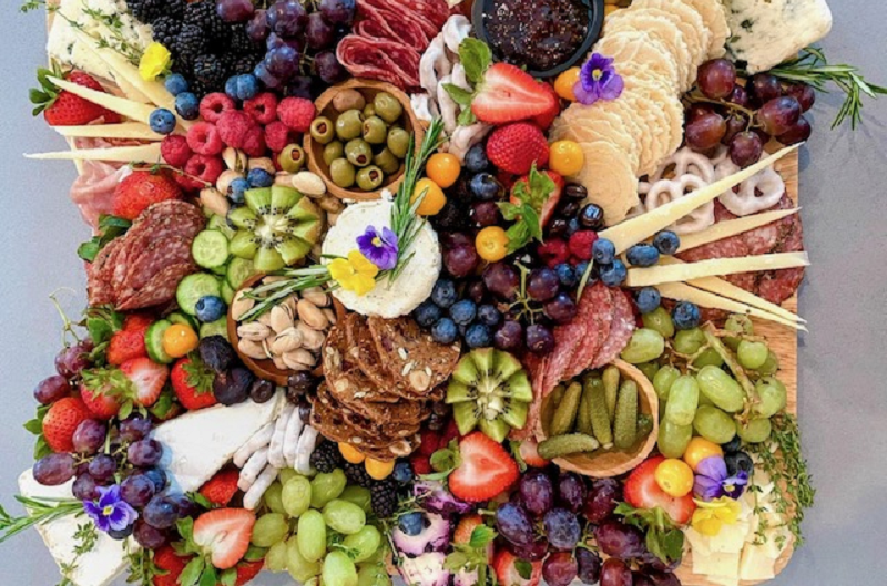 A charcuterie board filled with different cheese, vegetables, fruits and crackers.