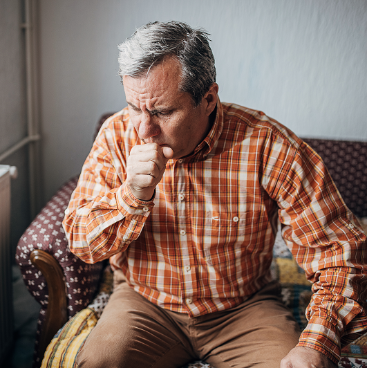 Older man coughing into his hand, managing a lingering cough.