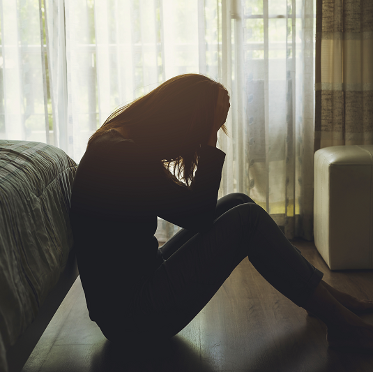 Woman sitting on the floor upset and emotional after a miscarriage