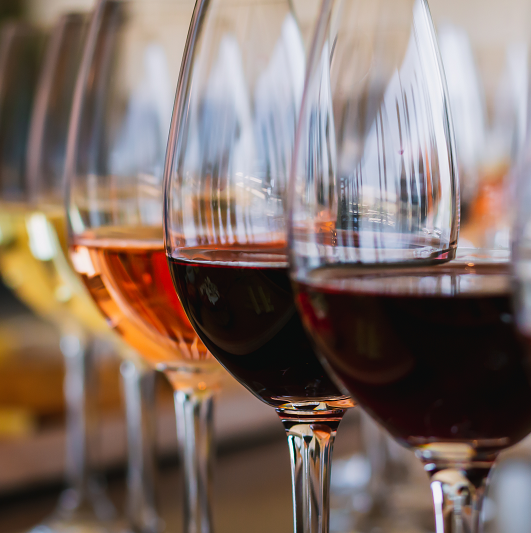 Close up view of wine glasses in a row, each having a different kind of wine it in. 