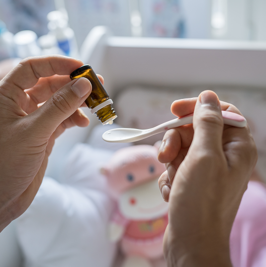 Close up of a father's hands preparing spoon with probiotic drops medicine for his baby