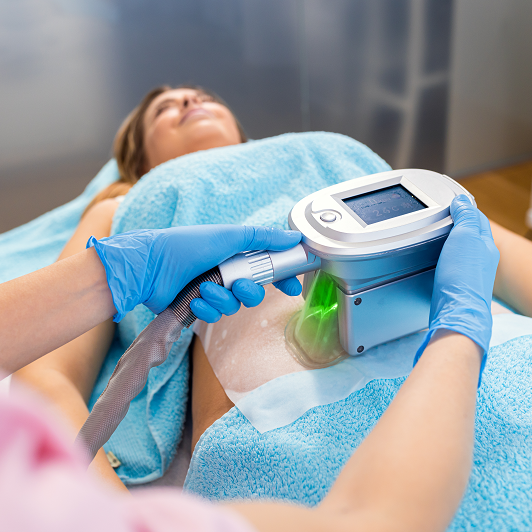 Therapist applying fat freezing cosmetic treatment, patient lying on a table.