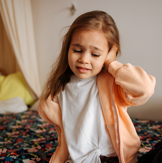 Young girl holding her ear in pain from a potential ear infection