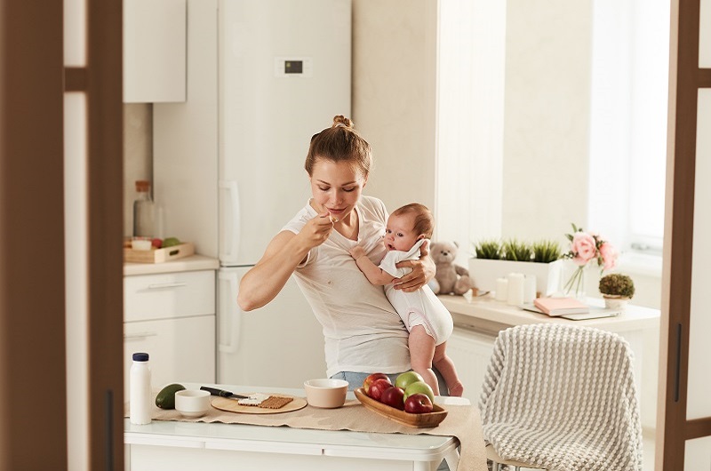 Mother holding her baby while having a healthy snack.