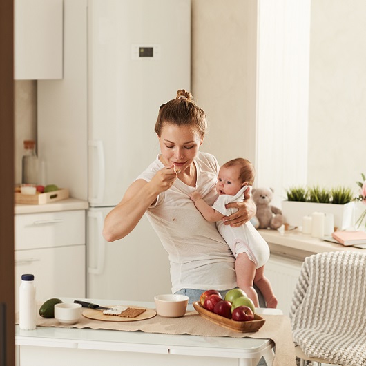 Mother holding her baby while having a healthy snack.