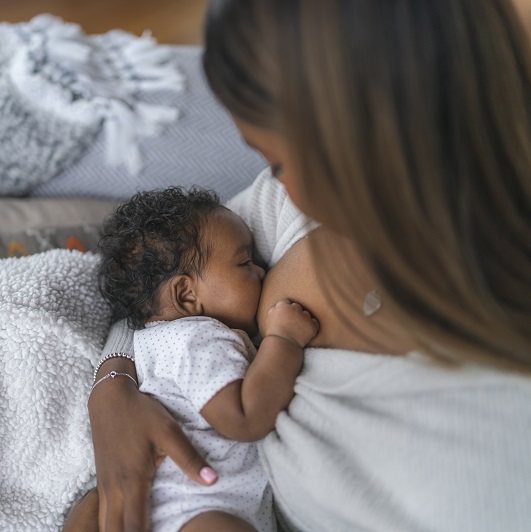 A woman breastfeeding her child on the couch at home.