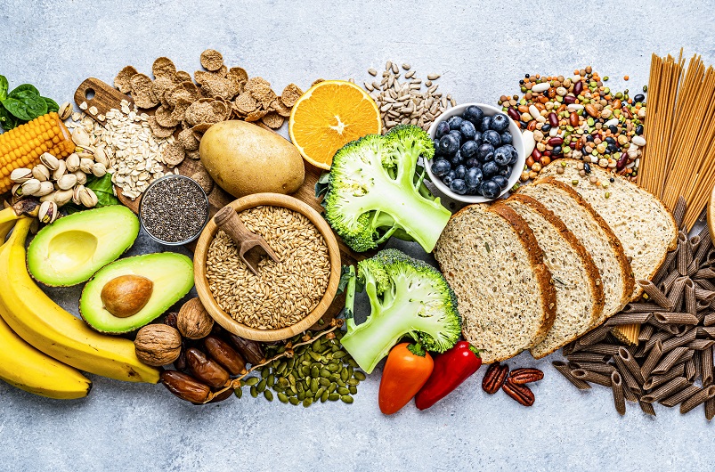 Overhead view of a large group of healthy foods like blueberries, broccoli, whole grains and nuts.