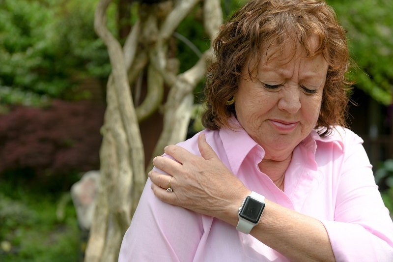 Woman holding her shoulder in pain from shoulder misalignment.