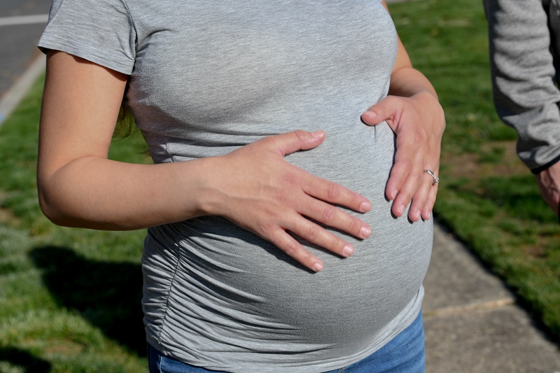 Pregnant woman feeling her belly - why abdominal separation happens during pregnancy