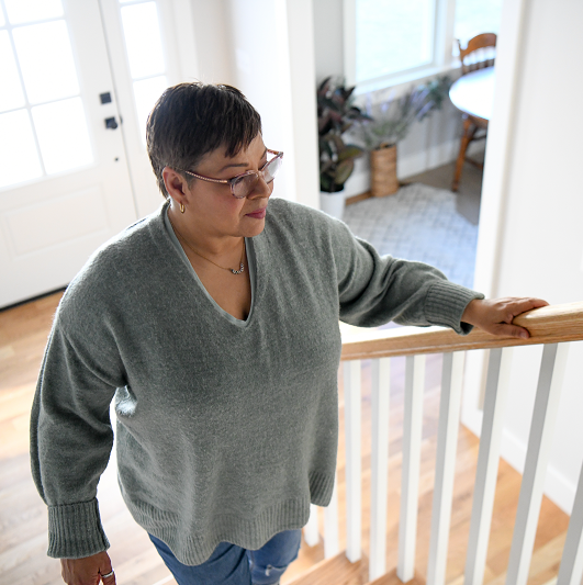 Woman walking up the stairs holding on to the railing.