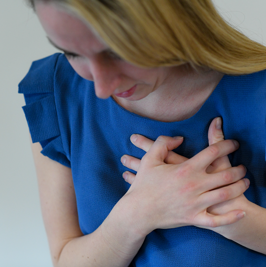 Young woman clutching her chest from heart palpitations. 