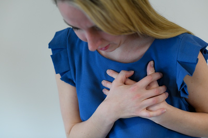 Young woman clutching her chest from heart palpitations.