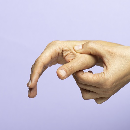 Close up of hands, on a purple background. One hand is putting pressure on the other hand, between the thumb and the index finger. Acupressure for stress relief.
