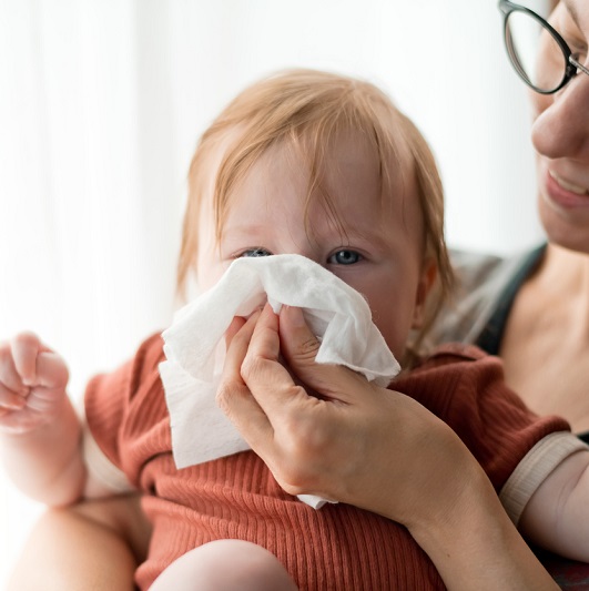 Mom helping baby clean their nose with a tissue.