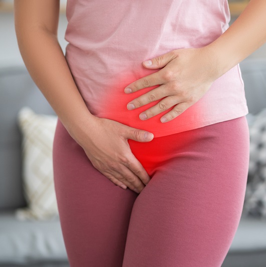 Woman with her hands on her lower stomach suffering from bladder issues.
