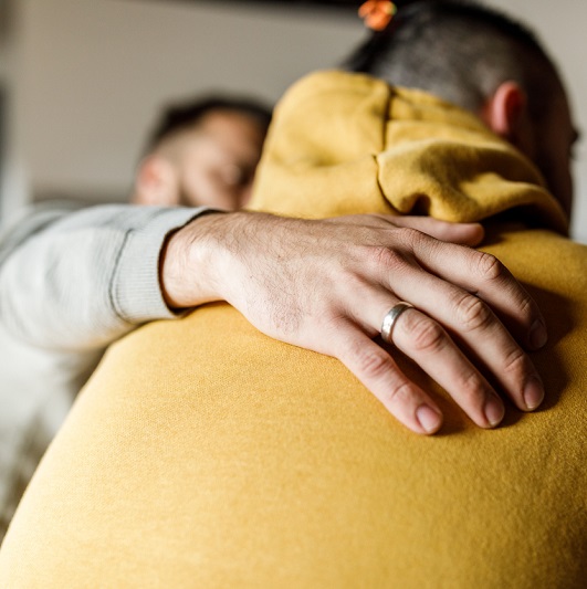Close up shot of a compassionate man embracing his friend, having an intimate conversation about his mental health and substance use.