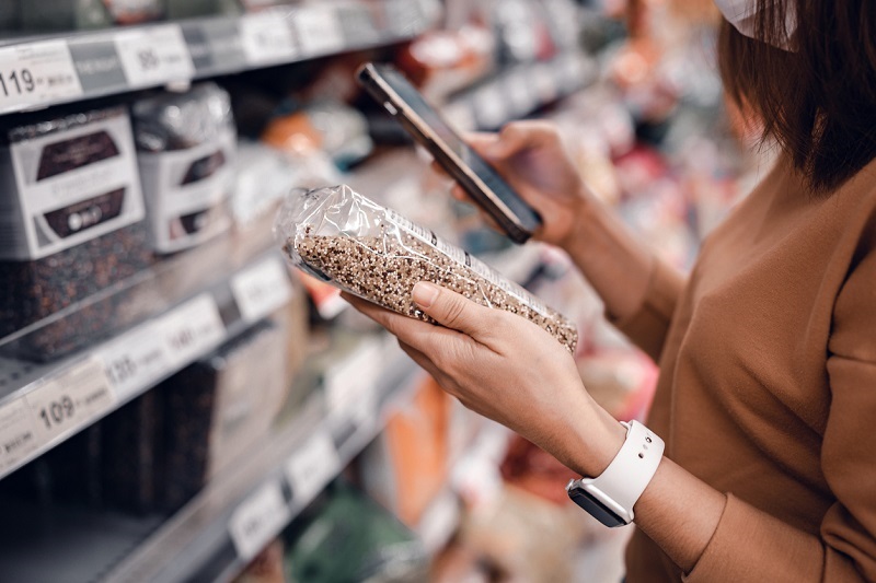 Woman shopping in supermarket and reading nutrition labels and ingredients.