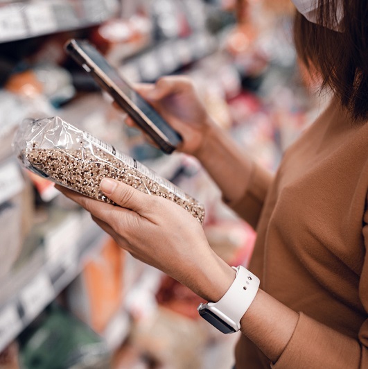 Woman shopping in supermarket and reading nutrition labels and ingredients.
