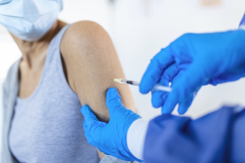 A close up shot of a senior patient getting a COVID vaccine in the arm.