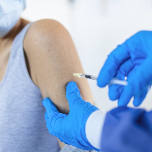 A close up shot of a senior patient getting a COVID vaccine in the arm.