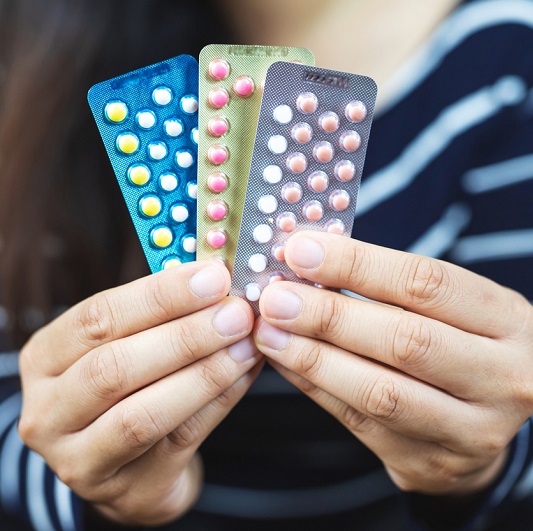 Woman's hands holding birth control pill options.