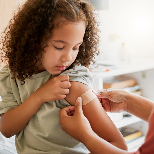 Young girl gets a bandaid placed on her arm after receiving the RSV antibody injection. 