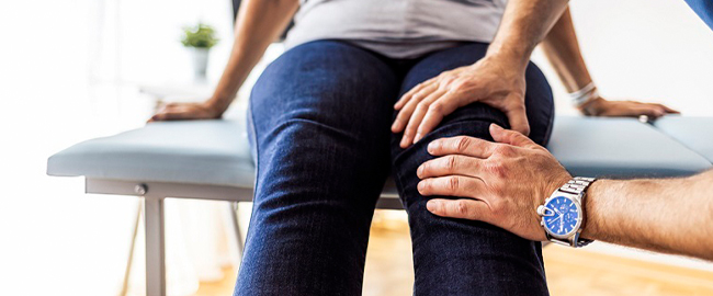 Doctor's hands on a patient's knee, evaluating for osteoarthritis. 