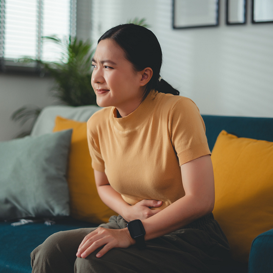 Woman holding her stomach, looking toward the sides, feeling gas pains, holding in a fart. 