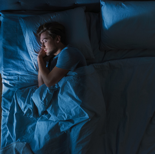 Man sleeping in a dark room in his bed.