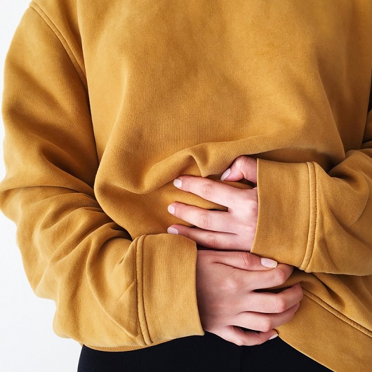 close up of a woman holding her stomach, feelin a hernia