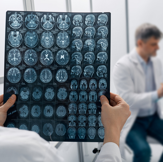 Male patient consulting with a neurologist while another physician is looking at MRI brain scans.