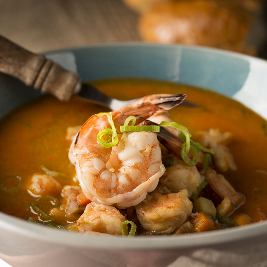 Shrimp and white bean stew in a bowl with a spoon.