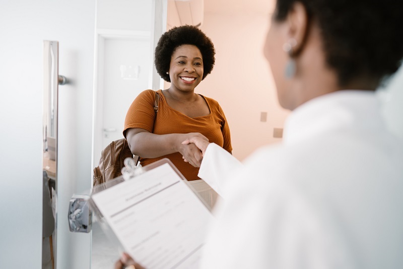 Woman shaking the doctor's hand, arriving at the doctor's office.