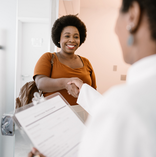 Woman shaking the doctor's hand, arriving at the doctor's office.