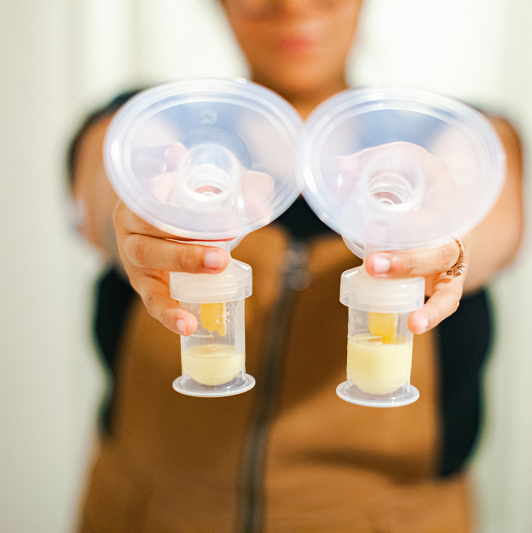 A mother showing off the collection of breast milk from pumping.