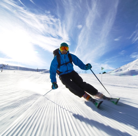 Man skiing down a slope in a bright blue jacket. 