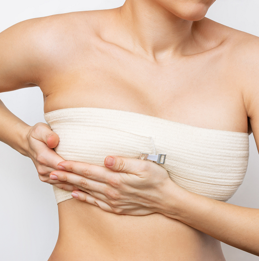 woman holding her bandaged breast after breast surgery