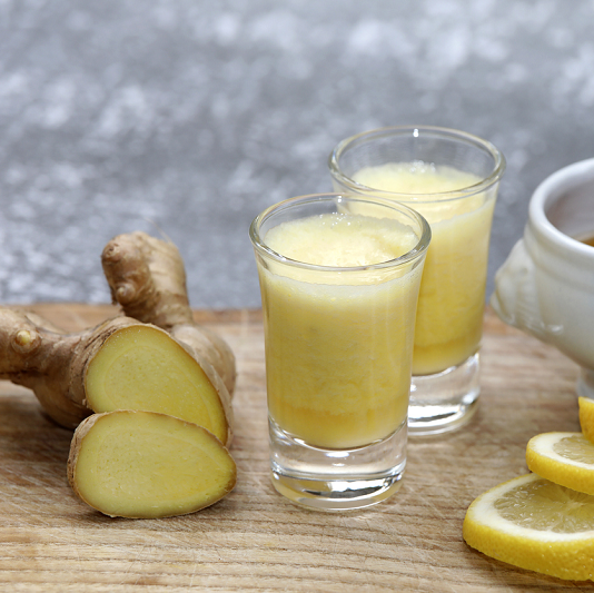 Drink with ginger root, honey and lemon on a wooden background.