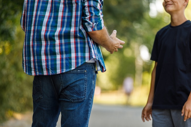 A father talking to his teenage son outside.