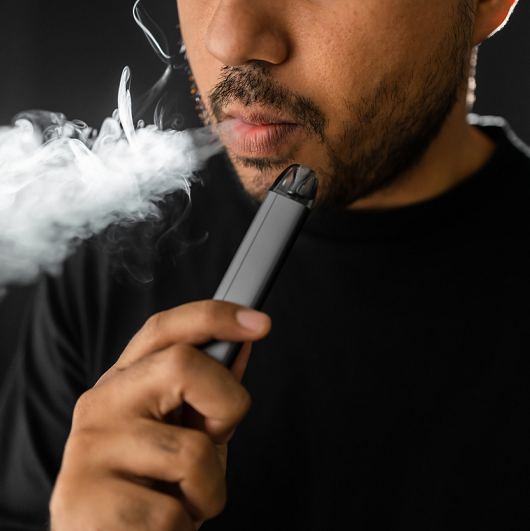 Close-up mouth of a man smoking an electronic cigarette.
