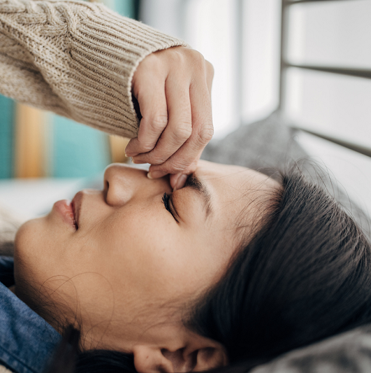  A woman lying with a severe headache. 