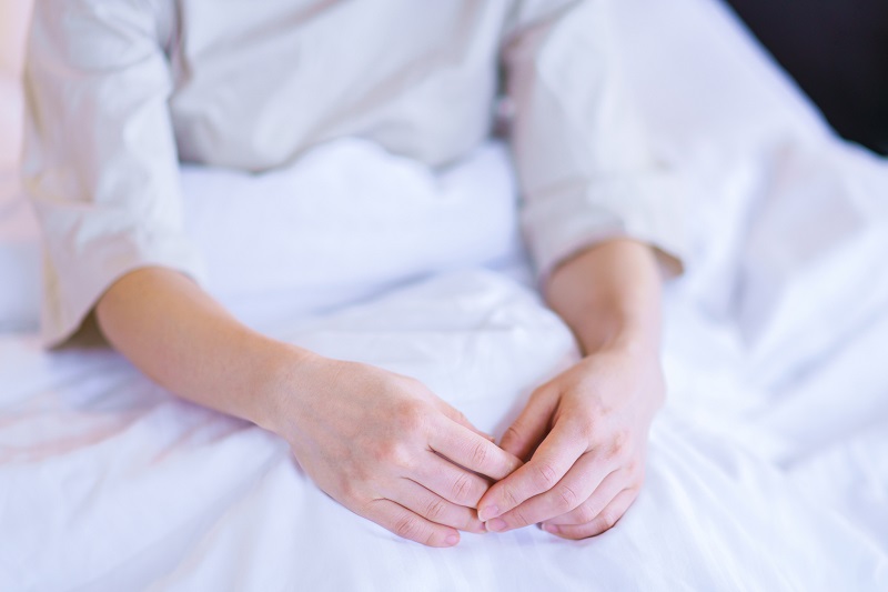 Woman's hands folded while resting in bed after surgery.