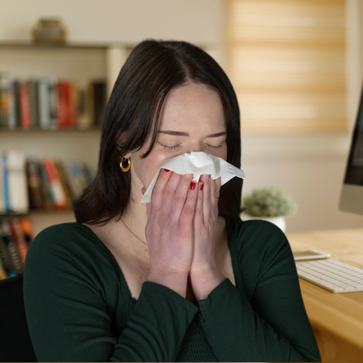 Young woman blowing her nose at home.