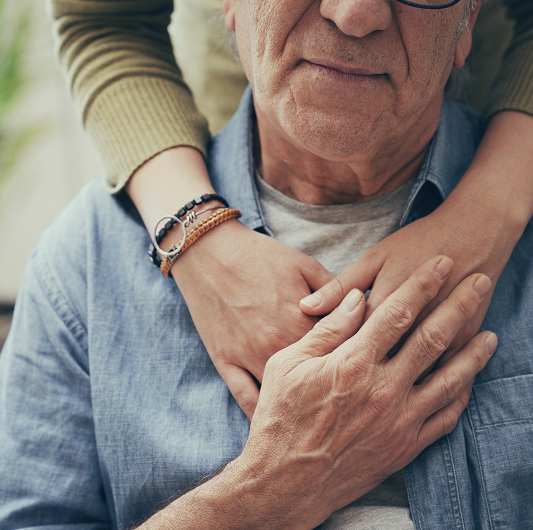 Woman's hand on a man's shoulder offering comfort.
