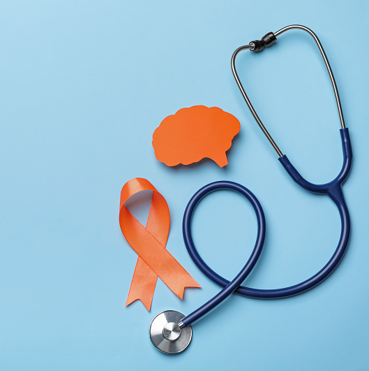 Orange ribbon, stethoscope and paper brain cutout on light blue background. Concept for multiple sclerosis awareness.